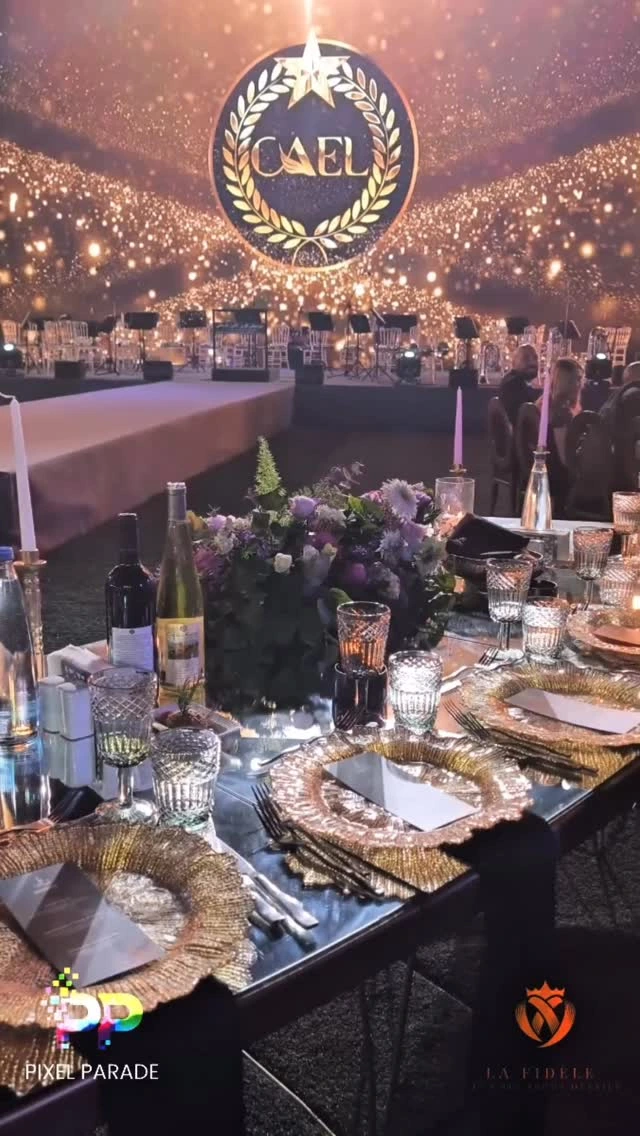 A gala table with flowers, glassware and gold-edged plates faces the CAEL stage. Pixel Parade and La Fidèle credits appear at the bottom.