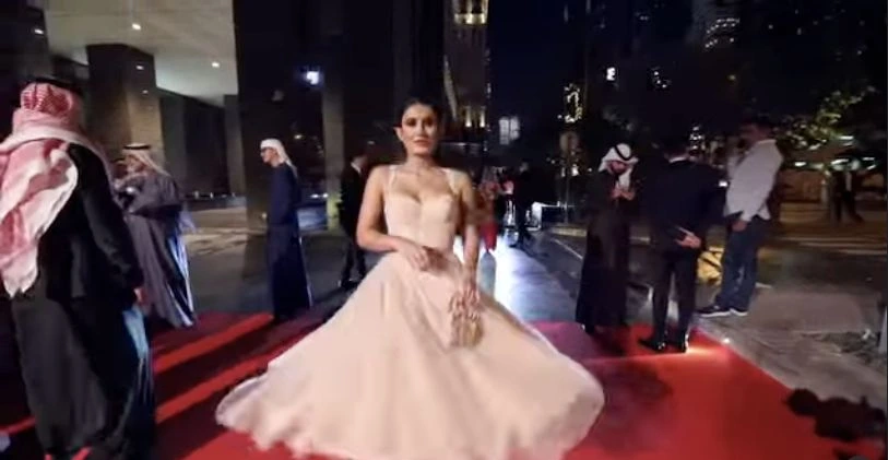 A guest in a full-length pale gown arrives on the red carpet at CAEL in 2021.