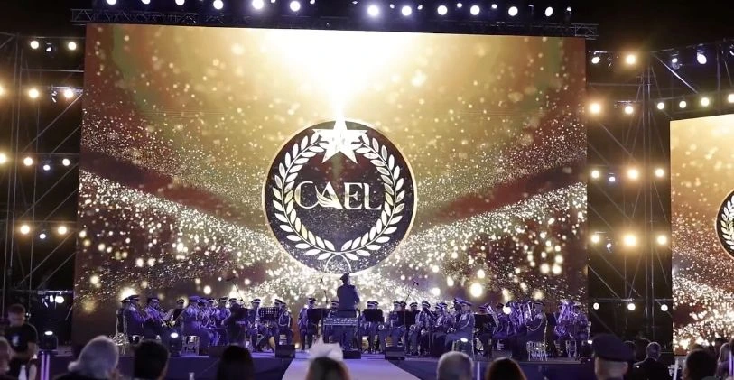 CAEL’s gold star-and-laurel emblem fills the stage screen, with the ensemble seated below.